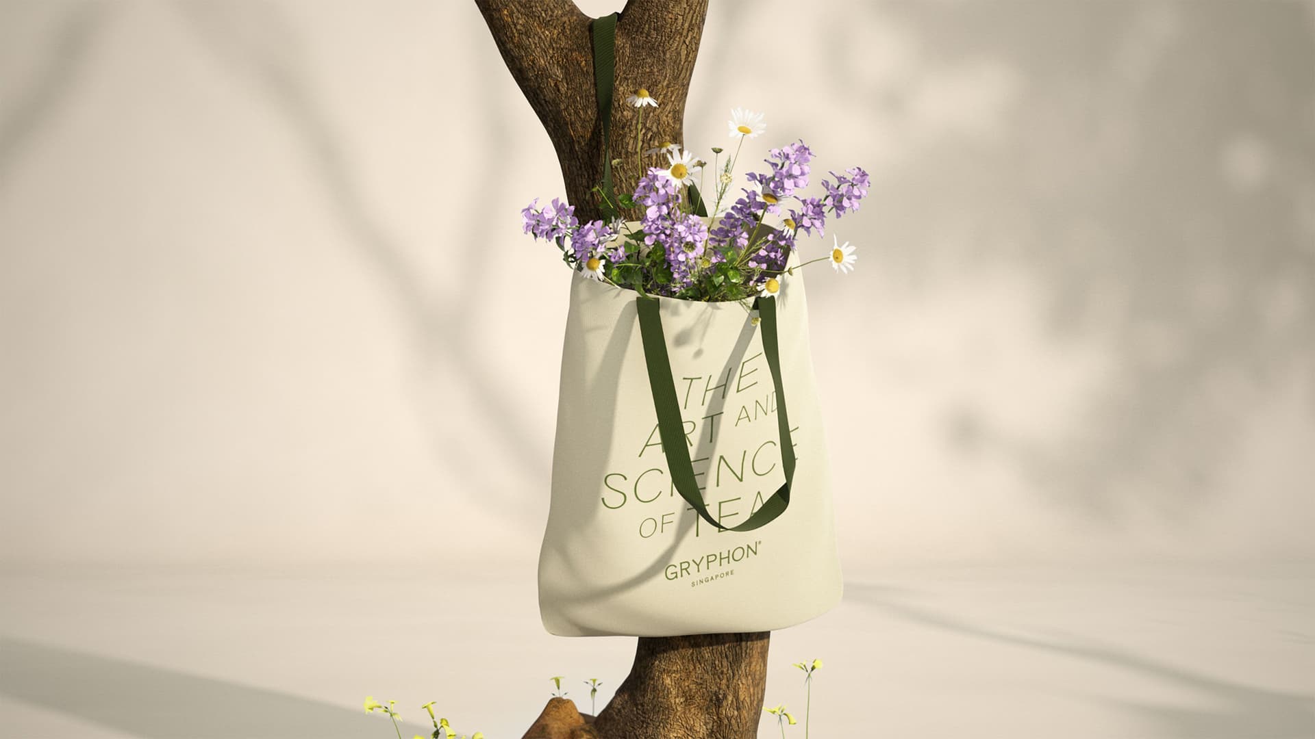 Gryphon's The Art and Science of Tea Tote Bag, styled with flowers, hanging from a tree